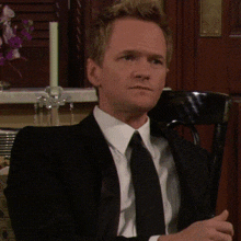 a man in a suit and tie is sitting at a table