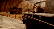 a child is sticking his head out of the window of a truck