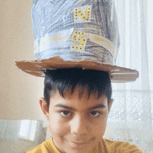 a young boy wearing a cardboard hat with the letter n written on it