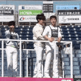 a group of young men are standing in front of a stadium with a sign that says howa on it