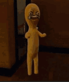 a yellow stuffed animal with a crying face is standing in a hallway .