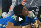 a man in a blue adidas shirt holds a banana in his hand