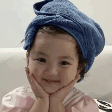 a little girl with a blue towel wrapped around her head smiles