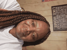 a woman with braids smiles in front of a sign that says like home