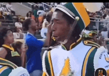 a man in a marching band uniform is standing in a crowd .