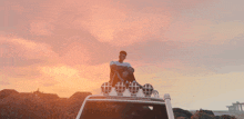 a man sits on the roof of a white truck