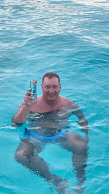 a man in a pool holds a can of truly