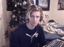 a young man wearing headphones is sitting at a desk in front of a computer keyboard in a bedroom .