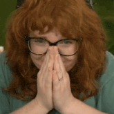 a woman with red hair wearing glasses and a ring on her finger