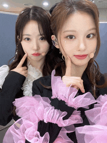 two girls posing for a picture with one wearing a pink dress