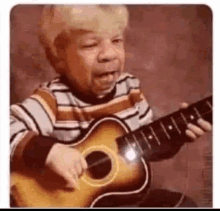 a young boy is playing a guitar with his mouth open .