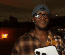 a man wearing sunglasses and a plaid shirt making a heart shape with his hands