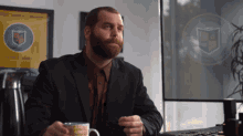 a man with a beard sits at a desk in front of a sign that says ' university of texas ' on it