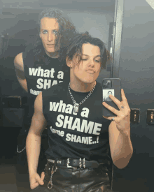 a man wearing a shirt that says what a shame is taking a selfie