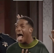 a man in a green sweater is sticking his tongue out while standing in front of a police officer .