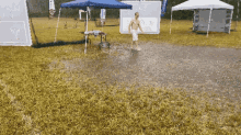 a man stands in a muddy field in front of a sign that says ' a & a ' on it