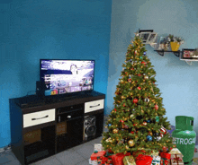 a christmas tree is in front of a television and a green propane tank that says etrogai