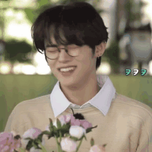 a young man wearing glasses is holding a bouquet of flowers and smiling