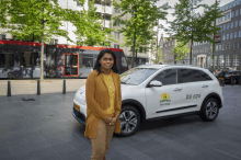 a woman stands in front of a car with the number av070 on the side