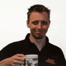 a man in a black shirt is holding a mug in his hand .