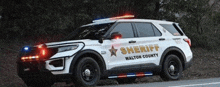 a white walton county sheriff 's car is parked on the side of the road