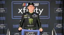 a man in a monster energy shirt stands in front of a sign that says xfinity