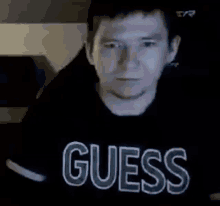 a man wearing a black shirt with the word guess on it .