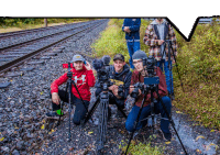 a boy in a red under armour sweatshirt is kneeling down while holding a camera