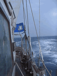 a blue flag with a shield on it is hanging from the side of a boat in the ocean