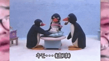 a group of penguins are sitting around a table holding a baby penguin .