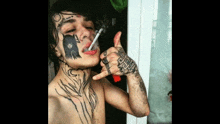 a shirtless man with a tattoo on his face smoking a cigarette