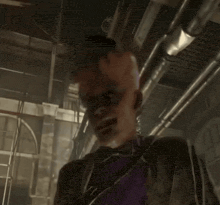 a man in a purple and black suit is standing in a dark room with his hands up .