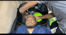 a man is washing his hair in a sink with a green bowl