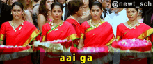 a group of women in red saris are standing in front of a crowd with a caption that says aai ga