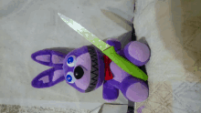 a purple stuffed bunny holds a green knife in its mouth