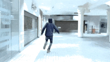 a man in a hooded jacket is running through a hallway