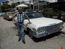 a man in a plaid shirt stands next to a white chevrolet