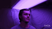 a man stands in front of a purple light that says saga space architects on the bottom