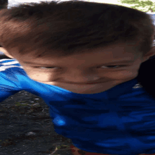 a young boy wearing a blue adidas shirt smiles