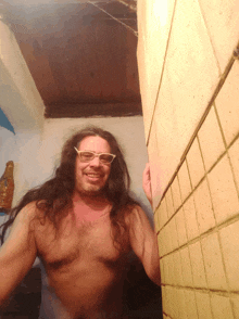 a shirtless man with long hair wearing white glasses