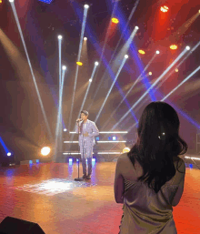 a man in a suit singing into a microphone on stage