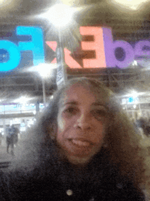 a woman taking a selfie in front of a sign that says e3b