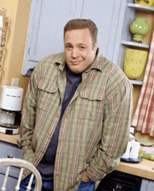 a man wearing a plaid shirt is standing in a kitchen