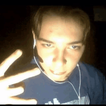 a young man wearing a headset and ear buds making a peace sign