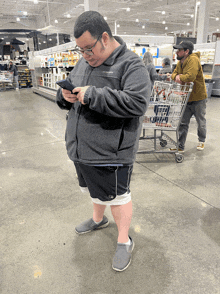 a man in a columbia jacket is looking at his phone in a store