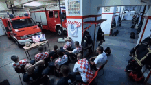 a group of men sit in a locker room in front of a fire truck with the number 93 on the back