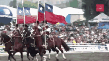 a group of people riding horses carrying flags in front of a crowd with a sign that says claro on it