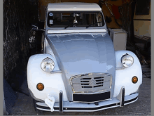 a silver and white citroen car is parked in a garage with a stuffed animal on the bumper