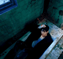 a man is laying in a bathtub with a bloody hand on his head