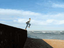 a man is jumping off a wall into the water